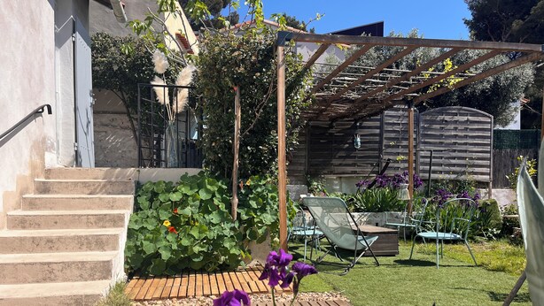 A garden with steps leading to a wooden deck, surrounded by greenery and flowers. - Panoramic view of Marseille and sunset, calm, nature and garden (Marseille)