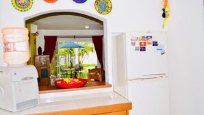 A kitchen with a water dispenser, a refrigerator with magnets, and a view of the outdoors through an archway. - Superior Villa Playacar – 500 m from the Beach & 5th Avenue (Playa del Carmen)