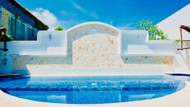 A swimming pool with a stone wall and a clear blue sky. - Superior Villa Playacar – 500 m from the Beach & 5th Avenue (Playa del Carmen)