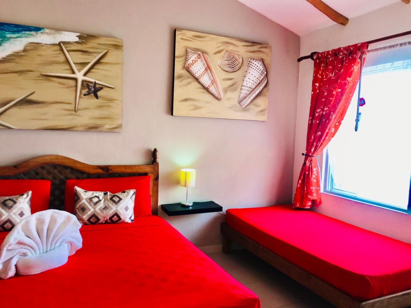 Una stanza con un letto, una panca e opere d'arte alle pareti.