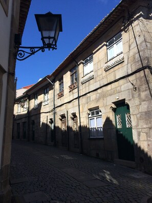 A cobblestone street lined with historic stone buildings, featuring ornate iron balconies and a green door. - CAPITAL Suite - START NOW! deluxe suites in historic center (Vila do Conde)