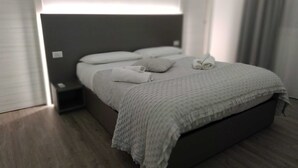 A modern bedroom with a large bed, a bedside table, and a nightstand. - The penthouse view with panoramic view (Palermo)