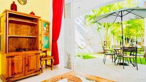 A room with a wooden cabinet, a wicker basket, and a view of an outdoor patio with a table and chairs.