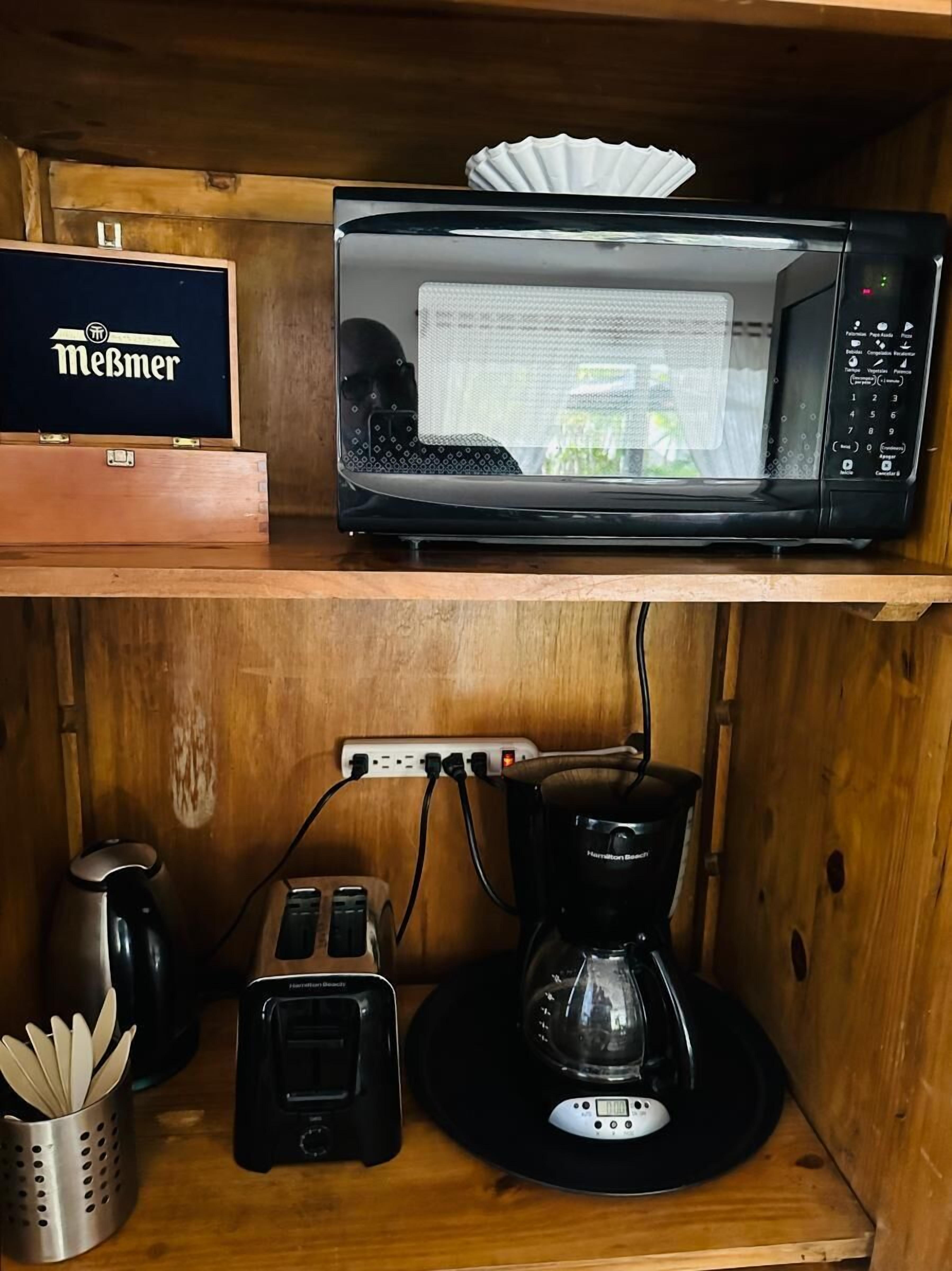 Eine Küche mit einer Mikrowelle auf der oberen Ablage und einer Kaffeemaschine auf der unteren Ablage.