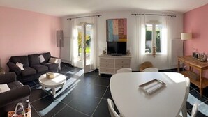 A living room with a sofa, a dining table, a TV, and a cabinet.