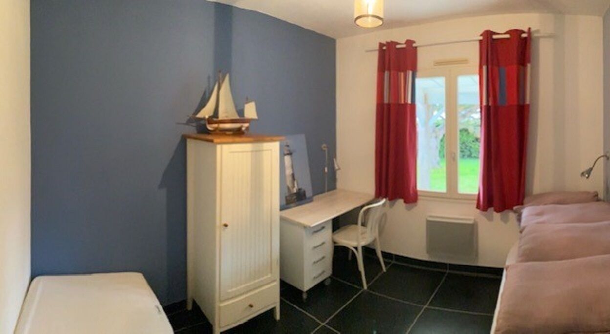 Een slaapkamer met een bed, een bureau, een stoel, een kledingkast en een raam met gordijnen.