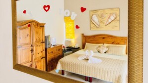 A hotel room with a wooden wardrobe, a bed with a white duvet, and a wall-mounted artwork.
