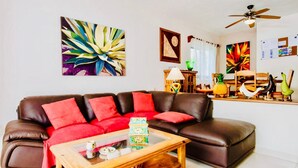 A living room with a brown leather sofa, red cushions, a wooden coffee table, and various decorative items. - Stunning private Comfort villa with pool in Playacar walk to the beach (Playa del Carmen)