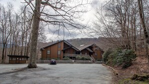 A lodge with a large wooden building, a parking area, and a forested backdrop. - Creekside Condo Walking Distance to Slopes! (Sugar Mountain)