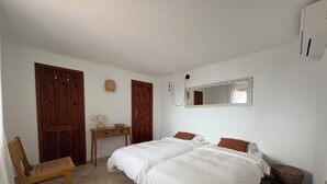 Un dormitorio con dos camas, una silla de madera, una mesita de noche y un espejo en la pared.