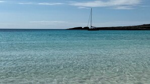 Vistas despejadas de un velero anclado cerca de una costa rocosa con aguas turquesas tranquilas.