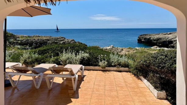 Un patio con sillones blancos y vistas al mar.