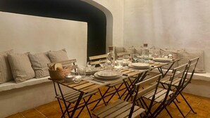 Comedor con una mesa larga dispuesta para seis comensales, rodeado de asientos acolchados a rayas.