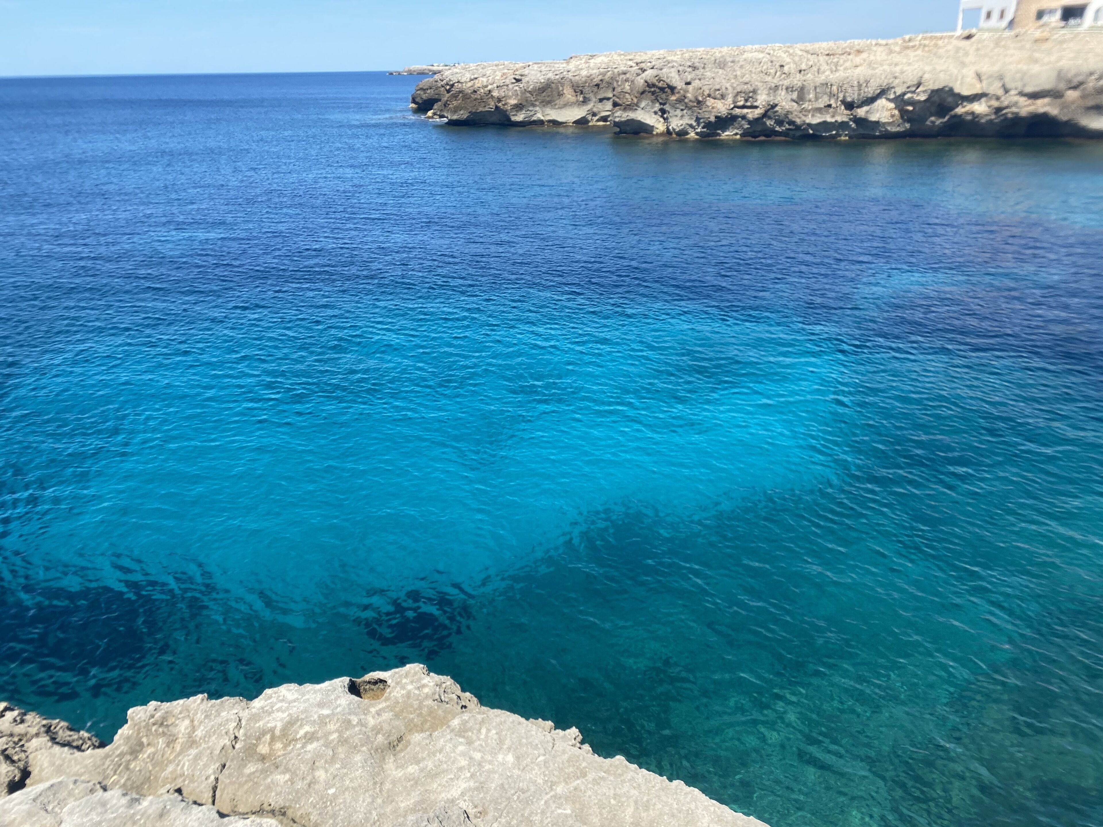 A coastal scene with clear blue water and rocky cliffs.
