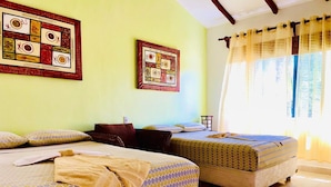 Habitación de hotel con dos camas, cabecera de madera, una mesita y una ventana con cortinas.