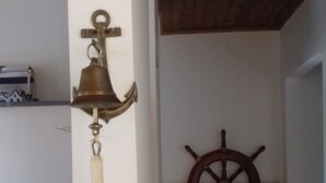 A room with a wooden ceiling, a wall-mounted ship's wheel, and a hanging bell with a tassel.