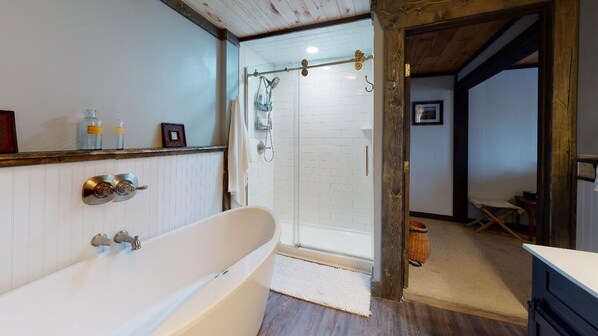 A bathroom with a freestanding bathtub, a glass-enclosed shower, and a wooden ceiling.