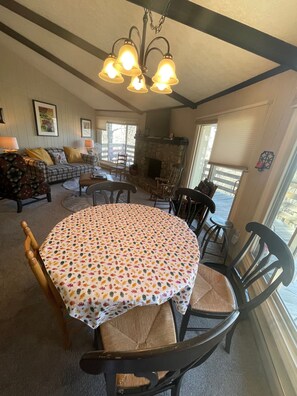 Un salon chaleureux avec une cheminée, un coin repas avec une table ronde et un canapé agrémenté de coussins.