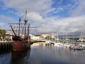 Ein historisches Schiff liegt in einer Marina vor einer Stadtlandschaft.