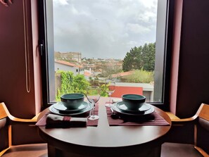 Ein Esstisch mit zwei Schüsseln und einem Weinglas, vor einem Fenster mit Blick auf eine Stadtlandschaft.