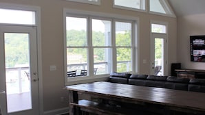 A spacious room with a large wooden table, multiple windows, and a ceiling fan. - Lake Front ★ No Wake w/ Dock ★ Gameroom ★ Carved FirePit ★ 2nd House Available (LaFollette)