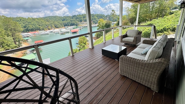 A wooden deck with wicker furniture, a view of a river, and a bridge in the distance. - Lake Front ★ No Wake w/ Dock ★ Gameroom ★ Carved FirePit ★ 2nd House Available (LaFollette)