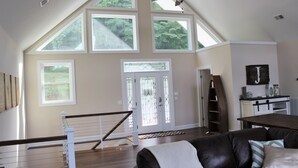 A spacious living room with a high ceiling, large windows, a ceiling fan, and a staircase leading to an upper level. - Lake Front ★ No Wake w/ Dock ★ Gameroom ★ Carved FirePit ★ 2nd House Available (LaFollette)