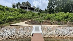 A wooden bridge over a river with a pathway leading to a building surrounded by greenery. - Lake Front ★ No Wake w/ Dock ★ Gameroom ★ Carved FirePit ★ 2nd House Available (LaFollette)
