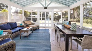 A covered outdoor seating area with wicker furniture, a dining table, and a ceiling fan. - The perfect Complex to fit your large group needs! (Saint Simons Island)