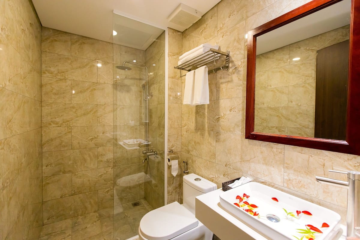 A modern bathroom with a glass-enclosed shower, a white toilet, and a sink with decorative flowers.