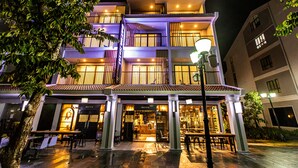 A multi-story hotel with a restaurant at the ground level, featuring outdoor seating and a visible entrance. - Bayya Hotel Phu Quoc (Phu Quoc)