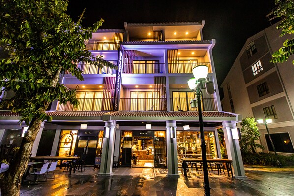 A multi-story hotel with a restaurant at the ground level, featuring outdoor seating and a visible entrance.