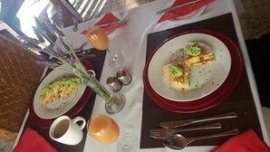 A table set for two with plates of food, a glass of orange juice, and a bottle of water. - Aloe Tree (Krugersdorp)