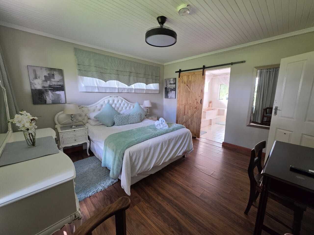 Un dormitorio con cama, mesitas de noche, un escritorio y una silla.