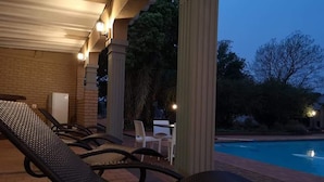A poolside area with lounge chairs and a brick wall. - Aloe Tree (Krugersdorp)