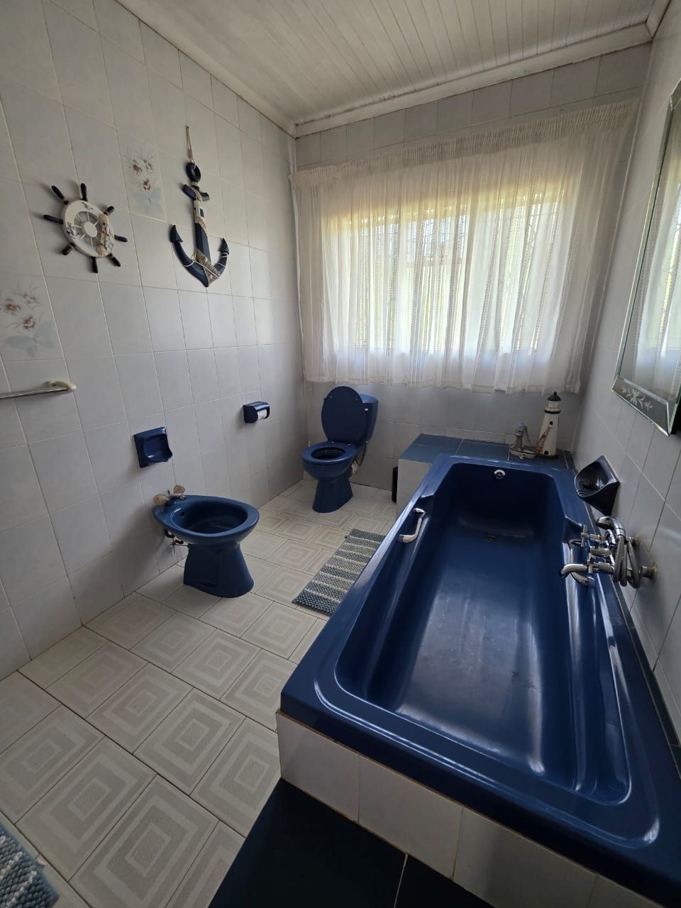 A bathroom with a bathtub, two toilets, a sink, and decorative wall art.