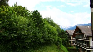 A hotel with multiple balconies, surrounded by lush greenery and mountains in the background. - Diablerets D 048 - MOUNTAIN apartment 4 pers (Veysonnaz)