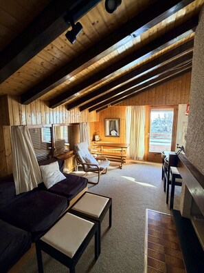 A cozy cabin with a wooden interior, a sofa, a chair, a table, and a fireplace. - Diablerets D 048 - MOUNTAIN apartment 4 pers (Veysonnaz)