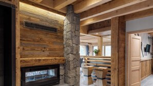 A spacious room with a stone fireplace, wooden beams, and a stone wall.