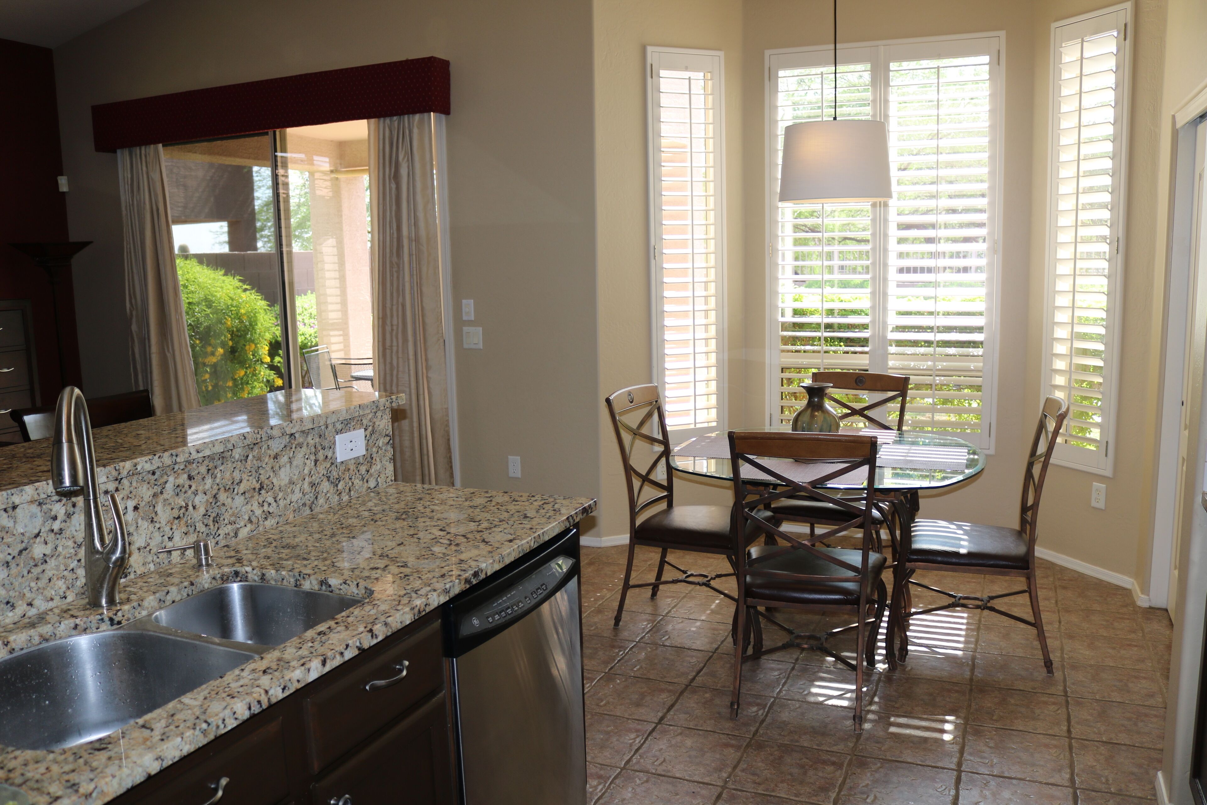 A kitchen with granite countertops, a dishwasher, and a dining area with a table and chairs.