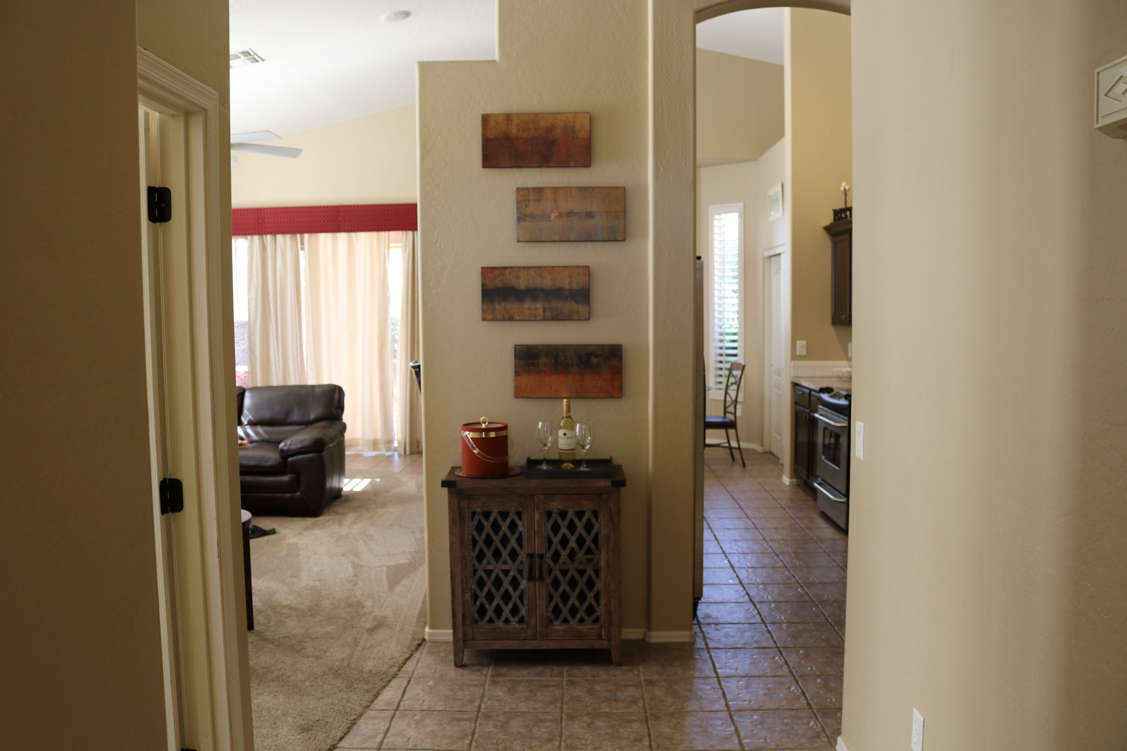 A living room with a leather sofa, a wooden console table with decorative items, and a kitchen in the background.