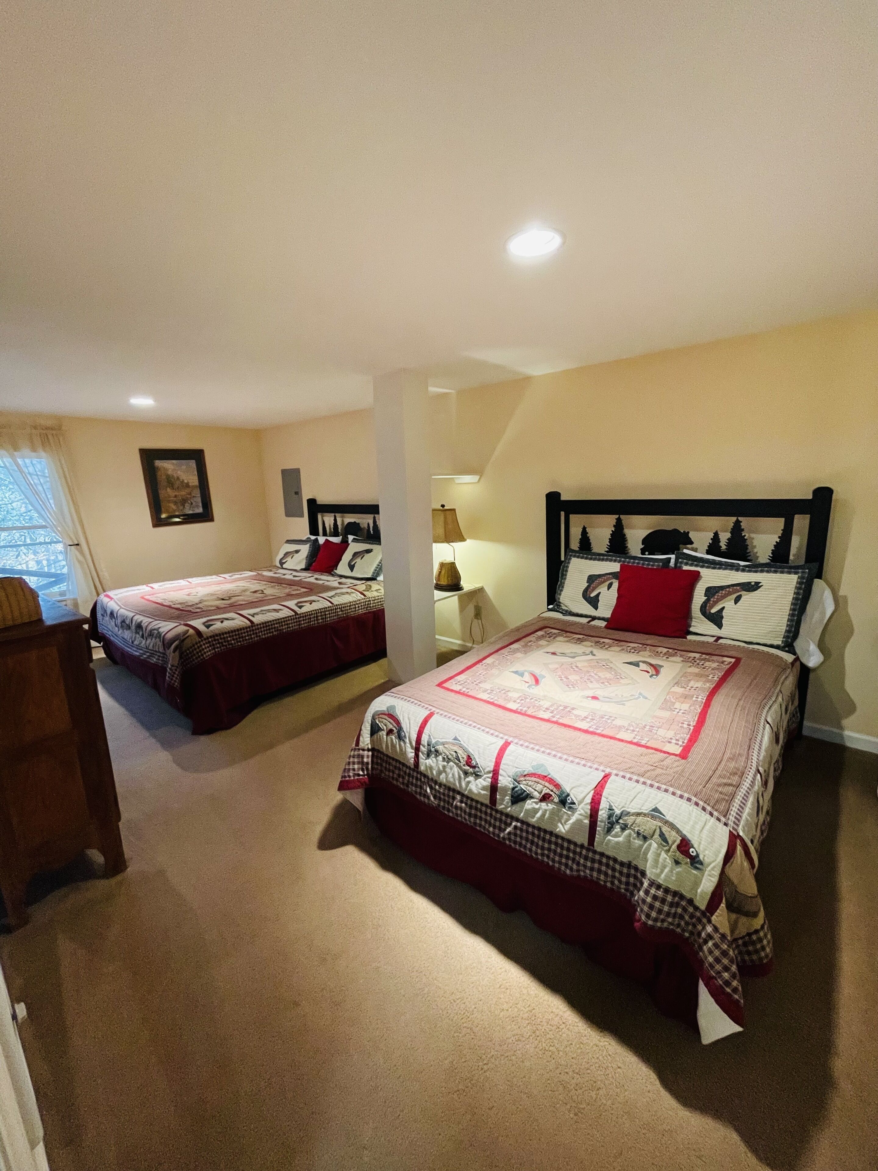 Une chambre avec deux lits, une table de chevet, une lampe et un tableau encadré au mur.