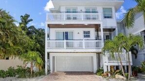 A two-story house with a white exterior, a balcony on the upper floor, and a garage.