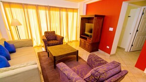 A living room with a sofa, armchair, and a television set. - Beautiful 1½ Bedroom Condo on the Sea of Cortez at Las Palmas Resort D-703A (Puerto Peñasco)