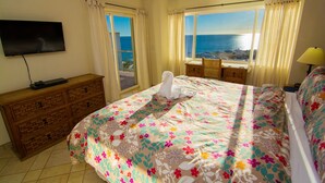 A hotel room with a bed, a TV, a wooden dresser, and a view of the sea. - Beautiful 1½ Bedroom Condo on the Sea of Cortez at Las Palmas Resort D-703A (Puerto Peñasco)