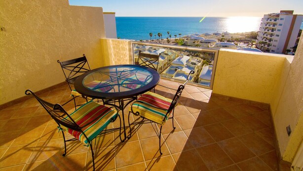 A balcony with a round table and chairs, overlooking a beach and cityscape. - Beautiful 1½ Bedroom Condo on the Sea of Cortez at Las Palmas Resort D-703A (Puerto Peñasco)