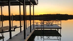 Eine Steg, der sich über ruhiges Wasser erstreckt, mit einem Sonnenuntergang im Hintergrund.