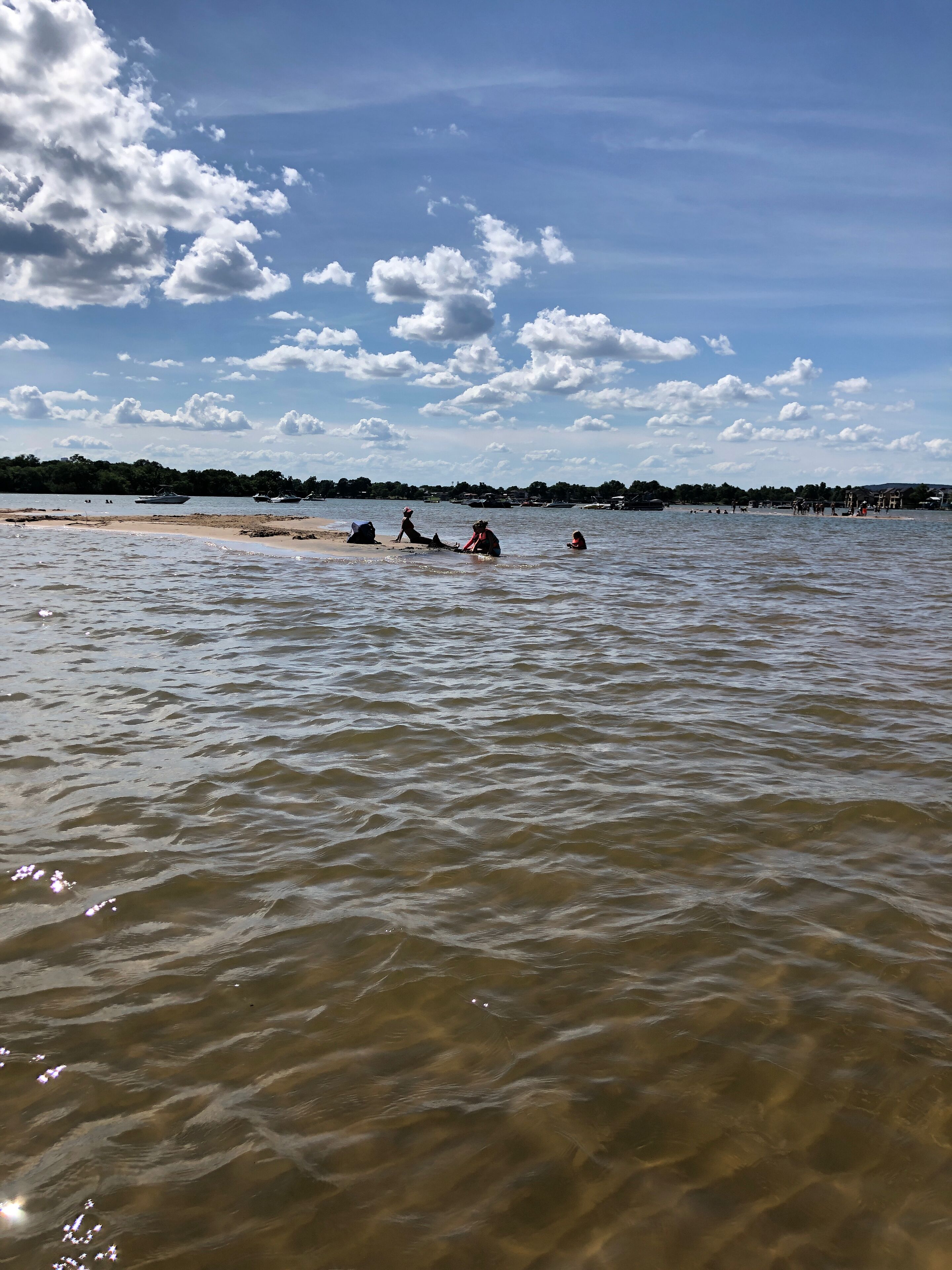 Een strand met boten en mensen in het water.