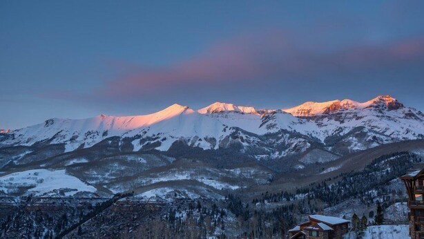 A mountain landscape with snow-covered peaks and a wooden cabin in the foreground. - Penthouse At The Peaks 623 (Mountain Village)