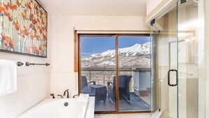 A bathroom with a bathtub, a glass-enclosed shower, and a view of a snowy mountain landscape. - Penthouse At The Peaks 623 (Mountain Village)